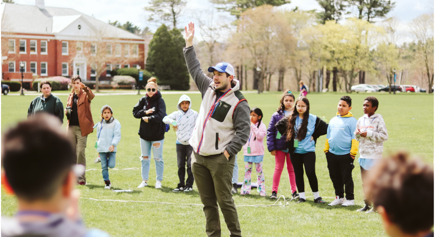 Man raising hang in circle of children playing a field game